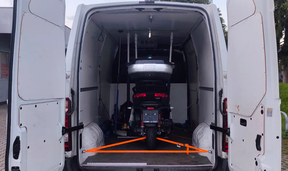 Motorrad im Laderaum eines Transporters, mit orangen Spanngurten gesichert